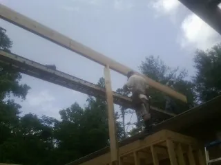 Carpenter setting a ridge beam over a new addition frame — Ice Dam Removal by Roofing Brothers in London