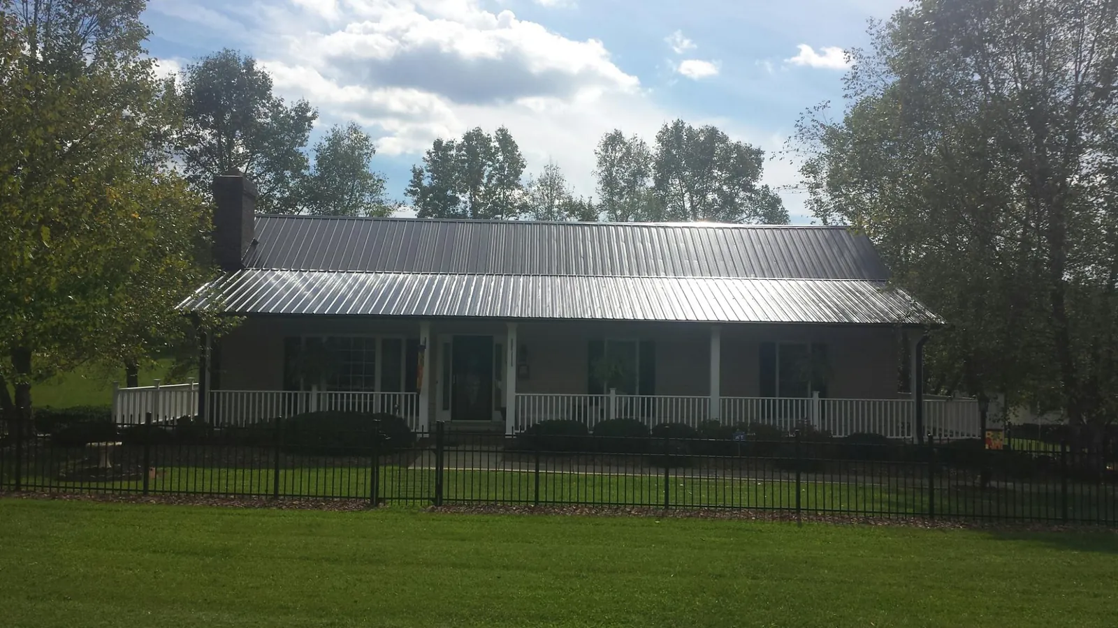 Gray metal roof on a brick ranch with a full width front porch — Gutter Guard Installation work by our crew in London