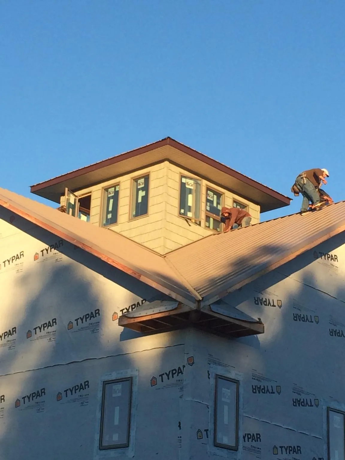 Roofers working around a rooftop cupola on a new metal roof at sunset — Roof Waterproofing in London by Roofing Brothers